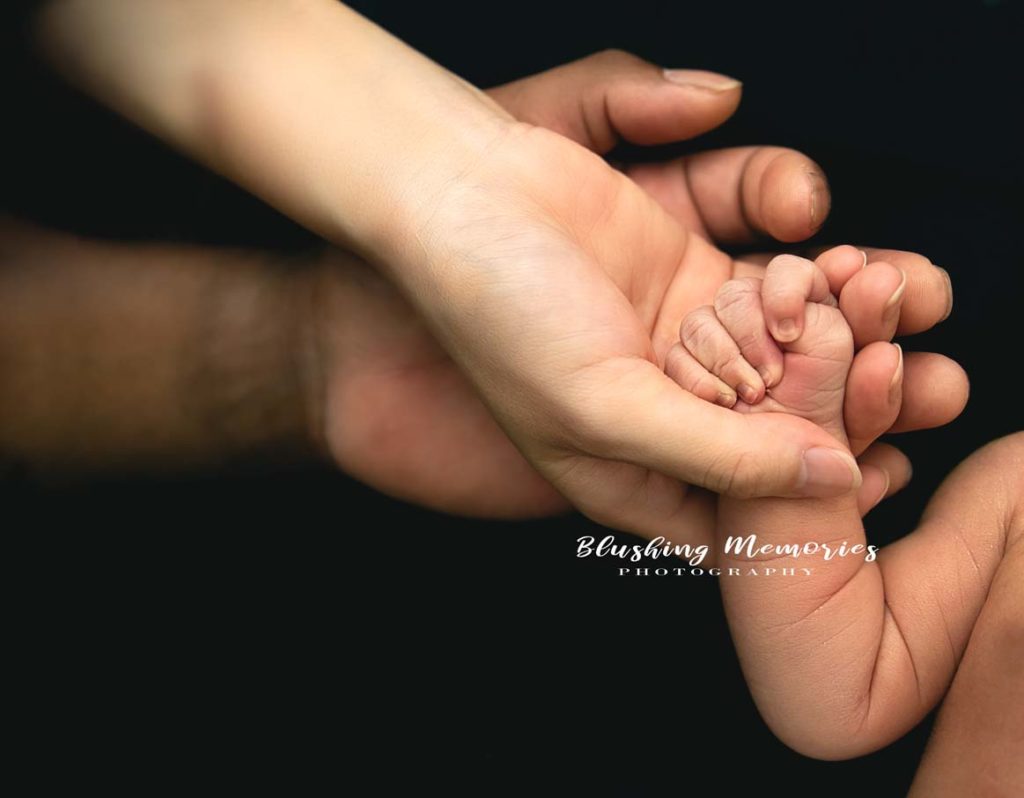 Newborn baby hands with mom and dad holding the fingers