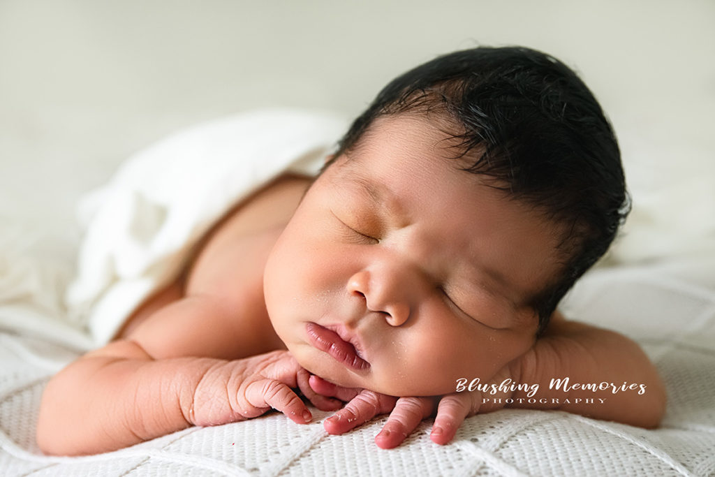 newborn baby boy posed in cheeks on hand position for a photo session