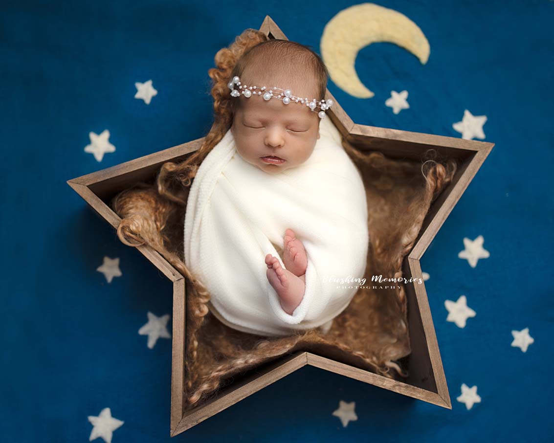 newborn baby girl photo portrait in a star shaped prop