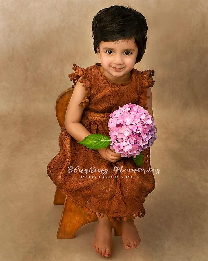 Portrait Session of a girl in the studio, holding flower sitting in the chair.