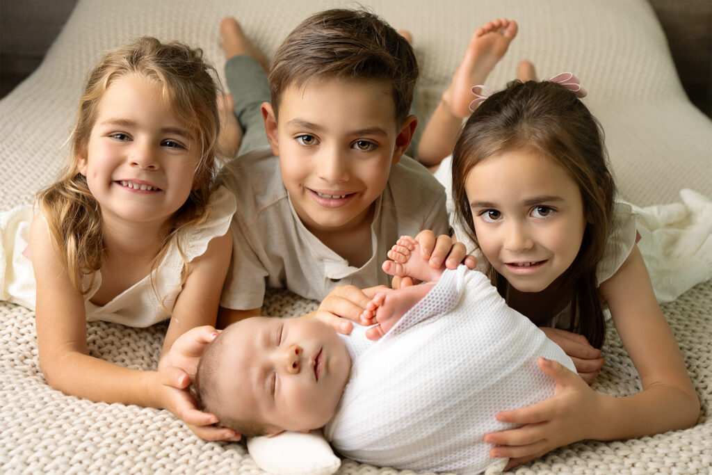 Newborn Baby boy with siblings on the bed, at Blushing memories Studio in El Dorado hills