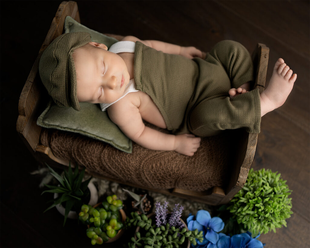 newborn baby boy in a green romper in a baby bed