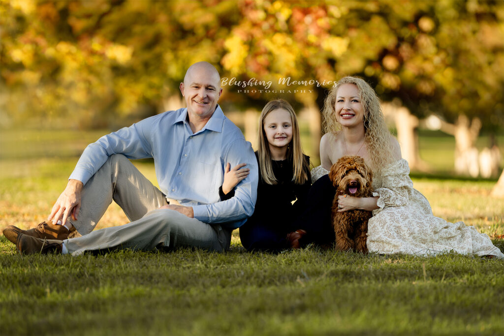 A loving family enjoying a fall outdoor photo session with their daughter and dog, captured by Blushing Memories Photography in El Dorado Hills, California.