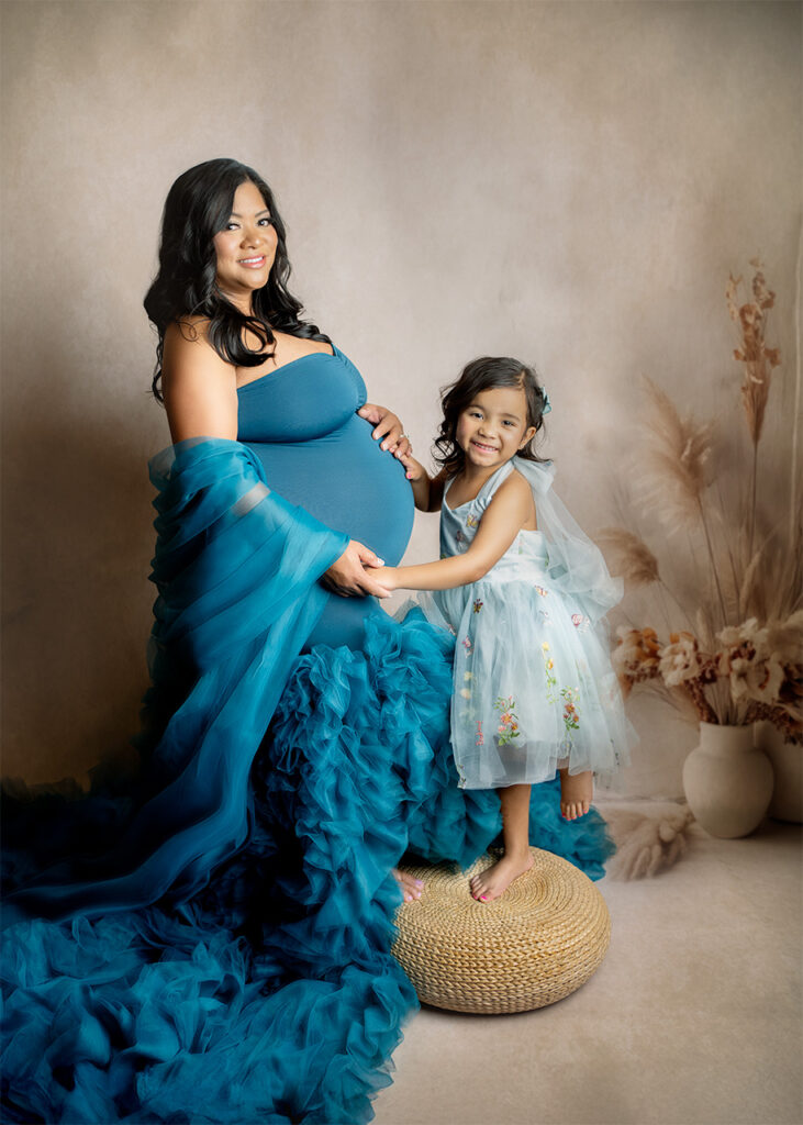 Studio maternity photo of a pregnant mother holding hands with her daughter during an intimate maternity session – Blushing Memories Photography, El Dorado Hills, Folsom, Sacramento, Bay Area
