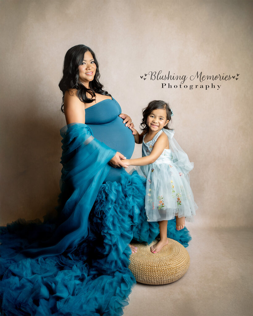 Studio maternity photo of a pregnant mother holding hands with her daughter during an intimate maternity session – Blushing Memories Photography, El Dorado Hills, Folsom, Sacramento, Bay Area