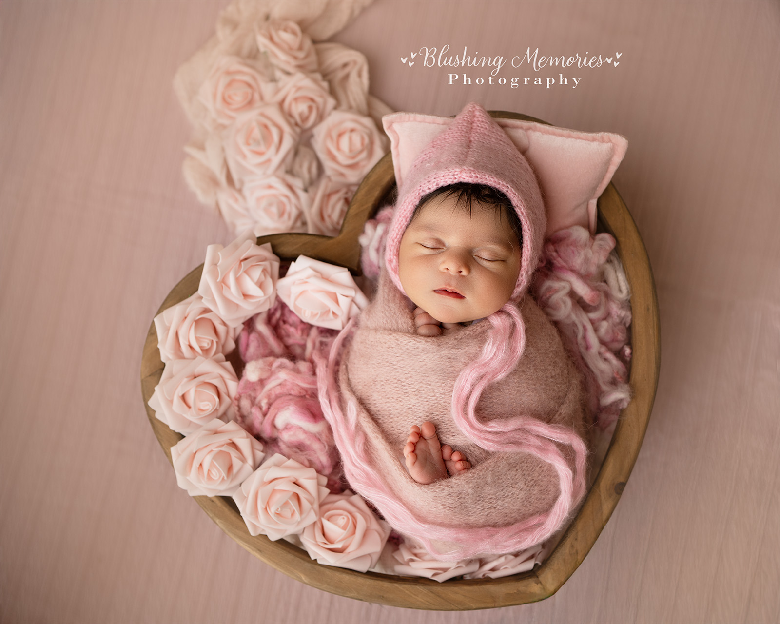 Sleeping newborn baby girl in pink basket prop during newborn photography session in Folsom California