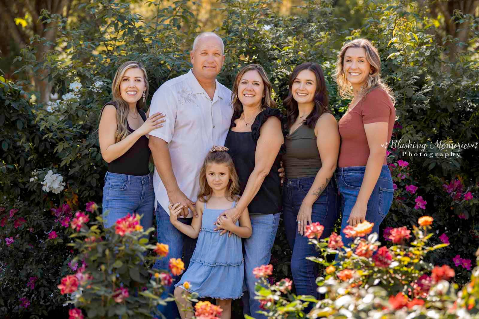 A multi generation family from Roseville poses for an outdoor photo session in Sacramento surrounded by colorful rose bushes.